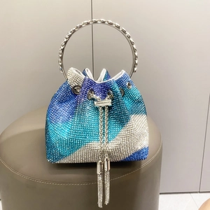 Dettaglio della borsa a secchiello in strass blu con manico in metallo e nappe