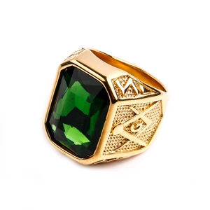 Dettaglio macro dell'anello massonico dorato con gemma verde smeraldo e simbolo della G