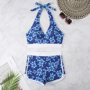 Flat lay of navy tropical floral bikini with halter top and white contrast piping detail