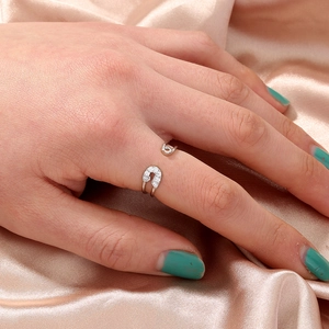 Detailed view of silver safety pin ring with white zircon stones on satin background