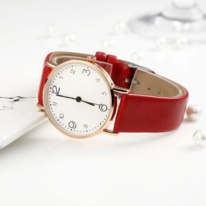 Detailed close-up of a red leather watch with rose gold case on a marble surface