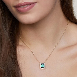 Elegant gold necklace featuring a rectangular green gemstone pendant on a female model