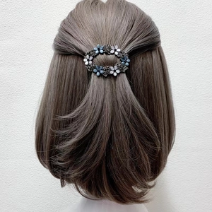 Macro view of a retro hollow alloy floral hair clip worn on a half-up brown hairstyle