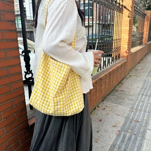 Detail of yellow and white checkered canvas tote bag showing thick texture and strap