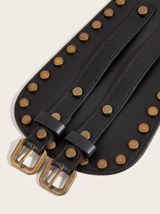 Close-up of black leather corset belt with brass rivets and metallic buckles detail