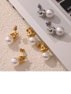 Detailed view of gold and silver rabbit stud earrings with white pearls on fabric