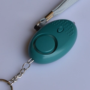 Detail view of water-drop shaped blue personal safety alarm with keychain and lanyard