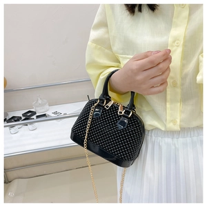 Close-up of black PVC shell bag with textured surface and golden chain strap detail