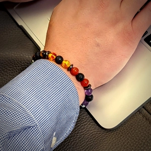 Natural lava stone and tiger eye chakra yoga bracelet worn by a person in a workspace