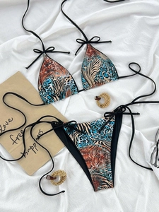 Flat lay of animal print bikini set with leopard patterns and side-tie strings on white fabric