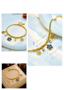 Detail of gold chain bracelet featuring blue enamel camellia and sparkling zircon charms