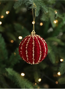 Detail of 8cm burgundy flocked Christmas ball with gold sequins on a festive tree branch