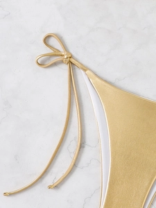 Detailed close-up of golden metallic triangle bikini top with knot tie and white lining