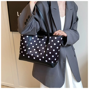 Polished black tote bag with white polka dots featuring high-quality leather handles
