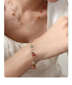 Close-up of gold chain jewelry set featuring colorful irregular natural stones on a model