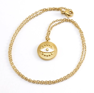 Detailed close-up of golden evil eye pendant with white enamel on a fine stainless steel chain