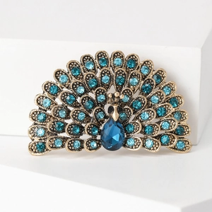 Vintage gold peacock brooch with sparkling blue rhinestones on a white background