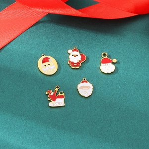 Detail of five gold enamel Santa Claus charms and sled pendants for DIY jewelry making