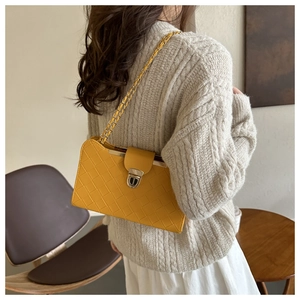 Detailed view of yellow woven texture shoulder bag with gold chain and metal buckle