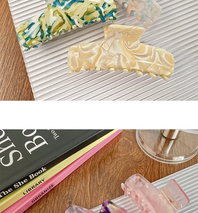 Detailed macro view of large acetate hair claws with premium marble and ink patterns
