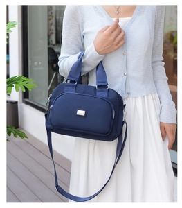 Detail of dark blue nylon handbag with silver hardware and shoulder strap on model