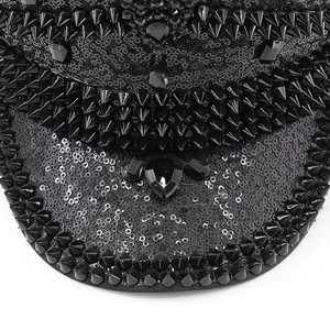 Macro shot of black sequined captain hat with punk style metal spikes and large faceted gems