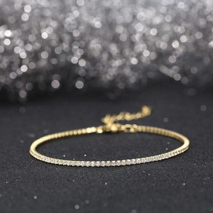 Macro shot of gold tennis bracelet with shimmering white zircons on black background
