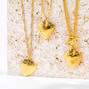Gold locket necklaces featuring water wave, paperclip, and T-bar chains on stone