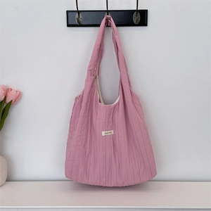 Close-up of pink pleated fabric tote bag with shoulder strap hanging on a wooden hook