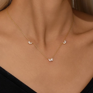 Close-up of a gold butterfly necklace with sparkling white zircons on a model's collarbone