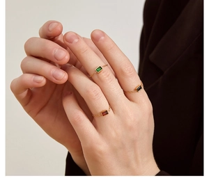 Detail of adjustable gold chain rings featuring emerald, black, and ruby rectangle stones