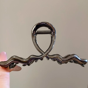 Detailed close-up of a metallic wavy hair claw clip with a high-shine gunmetal finish
