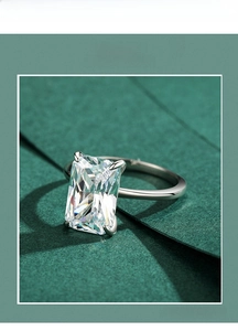 Macro shot of rectangular cut zircon ring with four-prong silver setting on green background