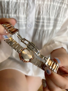 Detail view of two-tone stainless steel watch band and back case held by hands