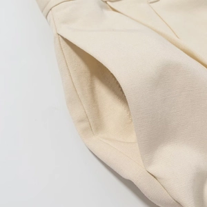 Dettaglio ravvicinato dei pantaloni beige a vita alta con trama in twill e cuciture tasche