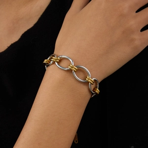 Détail d'un bracelet gourmette bicolore argent et or sur le poignet d'une femme