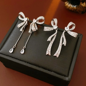 Detailed macro view of silver bow earrings with tassels and micro-set cubic zirconia crystals