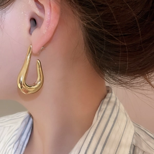 Close-up of elegant gold U-shaped earring worn by a model in a luxury side profile view