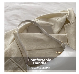 Close-up of white glossy patent leather handbag with gold zipper on tweed blazer