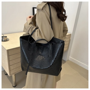 Mannequin portant un grand sac cabas noir en cuir tressé brillant pour un look de bureau