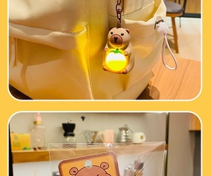 Glow-in-the-dark Capybara keychain with orange LED light on a white backpack and in packaging