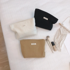 Three minimalist waffle texture makeup bags in cream, black, and camel with simple labels