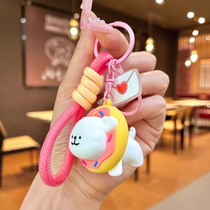 Detail view of cartoon dog keychain with pink donut collar and heart charm in hand