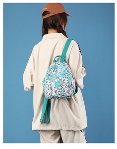 Detail view of mini floral nylon backpack with green leaf print on a blue background