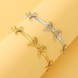 Detail of gold and silver snake chain bracelets with metallic bow charms on display