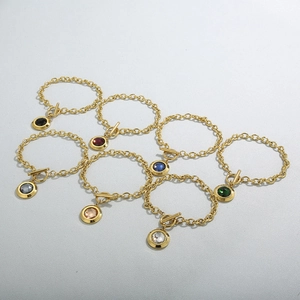 Golden OT buckle bracelet featuring colorful crystal pendants in a flat lay display