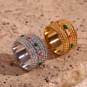 Detail of bohemian wide rings in gold and silver with red and green gemstones