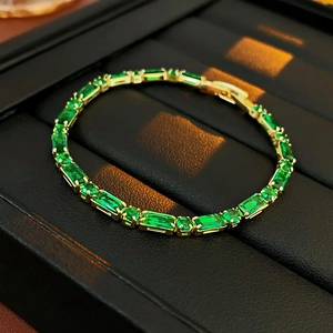 Detalle de pulsera tennis de circonita verde esmeralda bañada en oro sobre cuero negro