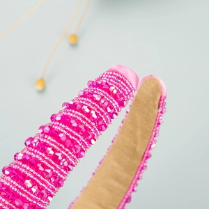 Detailaufnahme des rosa Perlenstirnbandes mit aufwendiger Handarbeit und luxuriöser Textur