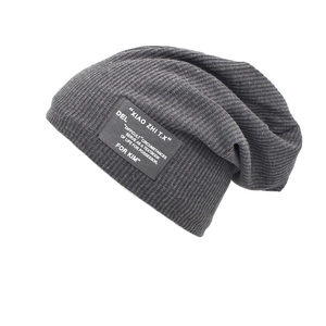 Macro detail of dark grey ribbed knit fabric and decorative woven patch on the beanie